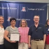 Image of five people smiling at camera; one is holding a certificate.